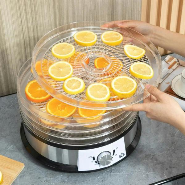Hands placing lemon and orange slices on trays inside a clear 5-tray dehydrator