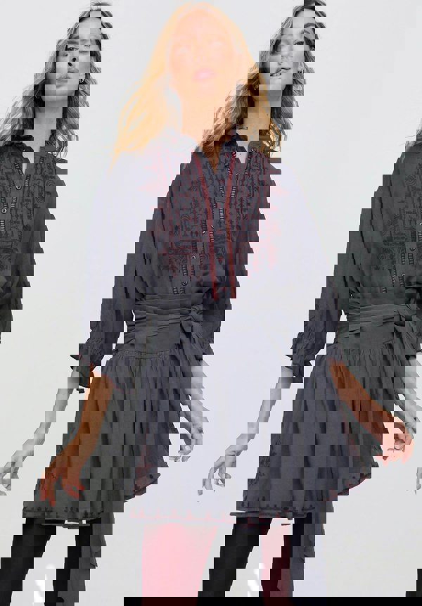 Woman wearing a gray dress with red embroidery on a white background