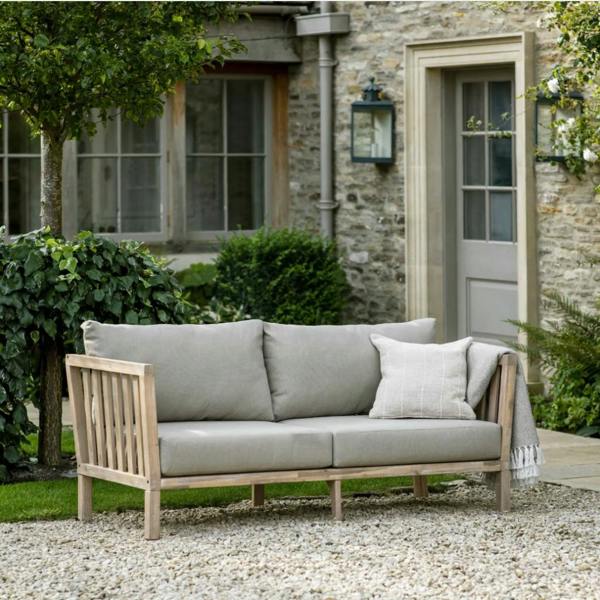 Traditional 2-seater garden sofa in whitewash acacia wood with soft grey cushions on a gravel patio.