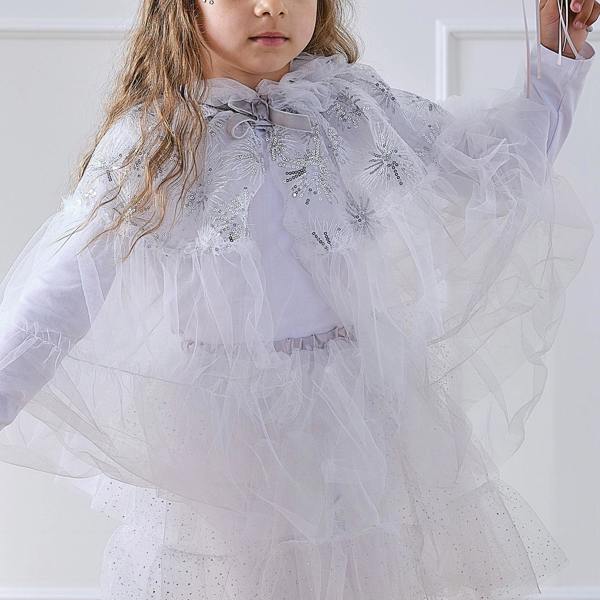 Close-up of a child wearing a white tulle winter fairy princess costume cape with silver sequin snowflake patterns and a silver velvet ribbon tie.