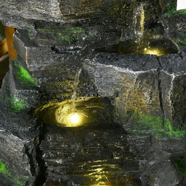 Close-up dark grey rock water fountain with warm white LED light and trickling water