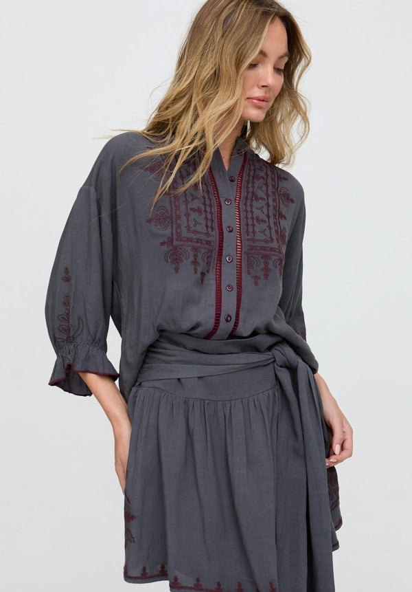 Woman wearing a gray dress with red embroidery on a white background