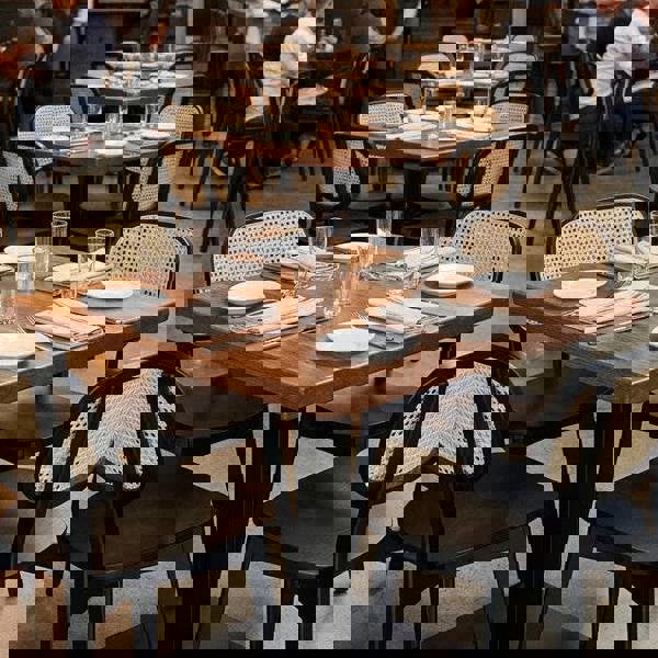 Dining area with tables, chairs, and people in a restaurant setting.