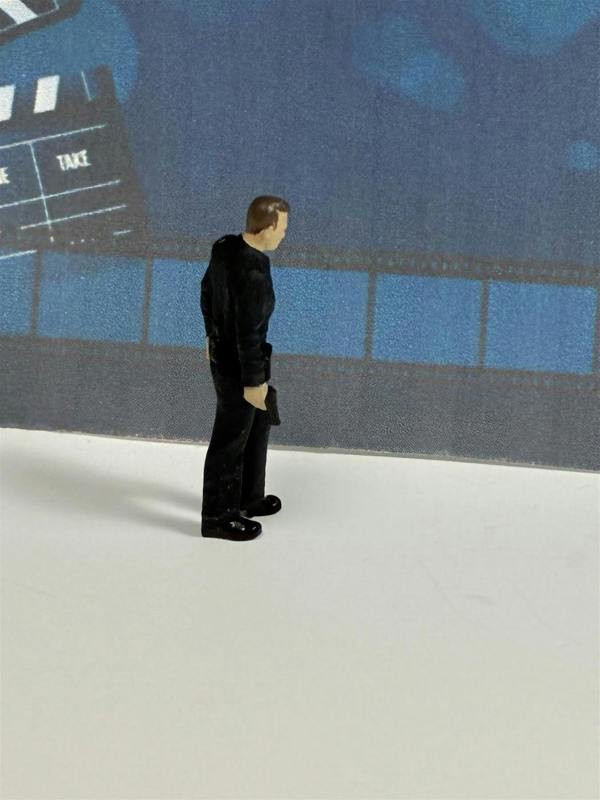 a toy figure of a man standing in front of a blue wall