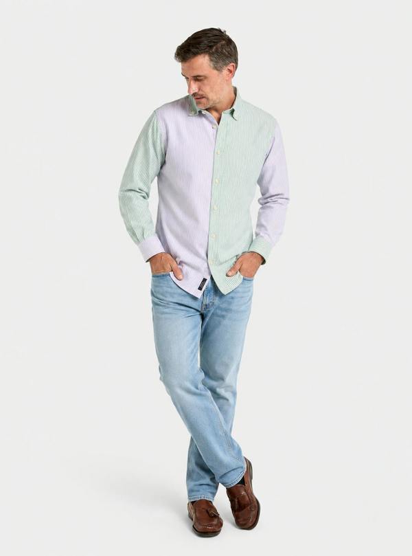 Man wearing a lilac and green patch stripe Oxford button-down shirt with blue jeans, relaxed full-length pose