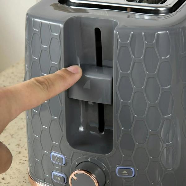 Grey toaster with crumb lever and browning control dial, hand pressing