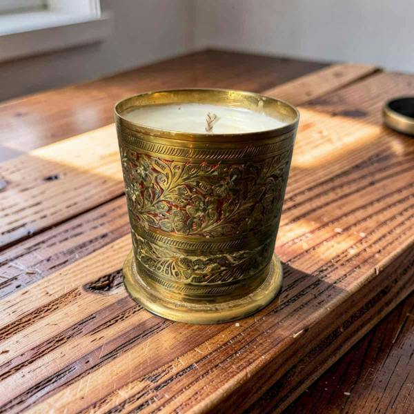 Decorative candle in an ornate brass holder on a wooden surface