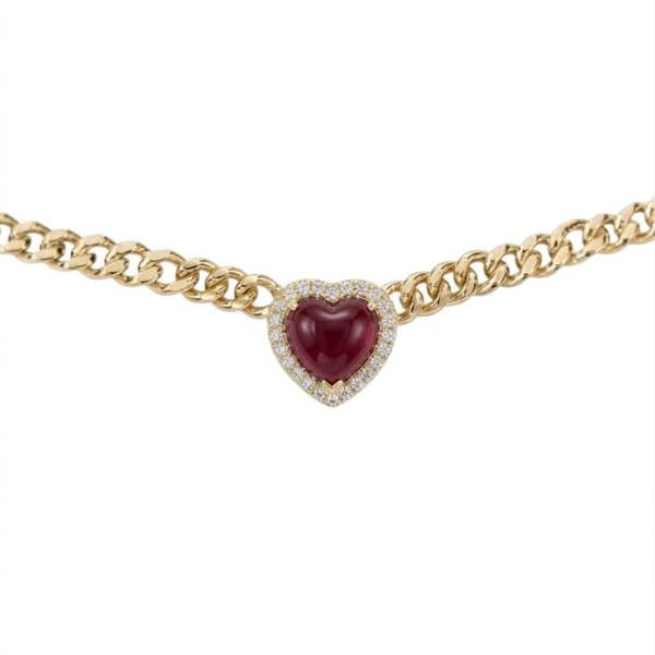 A gold chain necklace featuring a heart-shaped centerpiece with a deep red cabochon gemstone surrounded by a halo of small clear stones, shown against a plain white background.