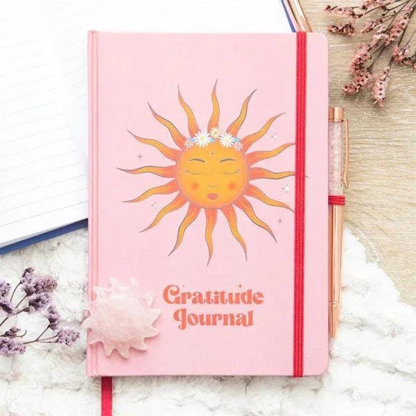 Pink gratitude journal with sun cover, red spine ribbon, and rose quartz pen