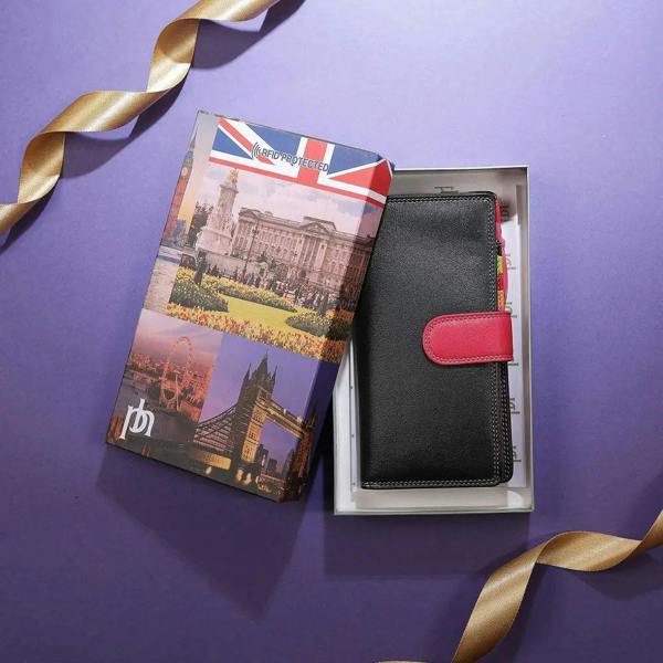 Black bifold purse with red accent and travel-themed packaging on a purple background