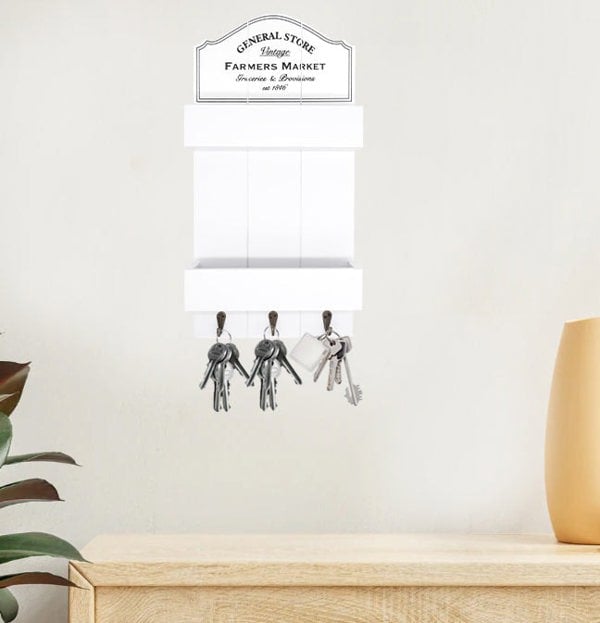 Decorative key holder with keys on a white wall above a wooden surface.