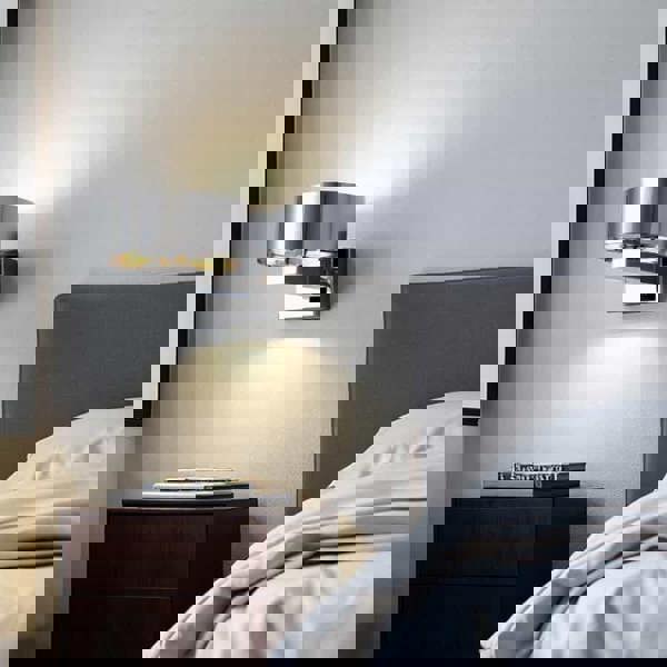 chrome bed side wall reading light mounted on the wall next to a bed in a minimalist bedroom