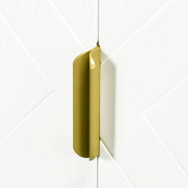 Gold door handle on a white under-sink cabinet with geometric panel design