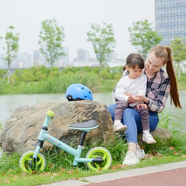 Kids using a light green balance bike with lime wheels while sitting on a rock