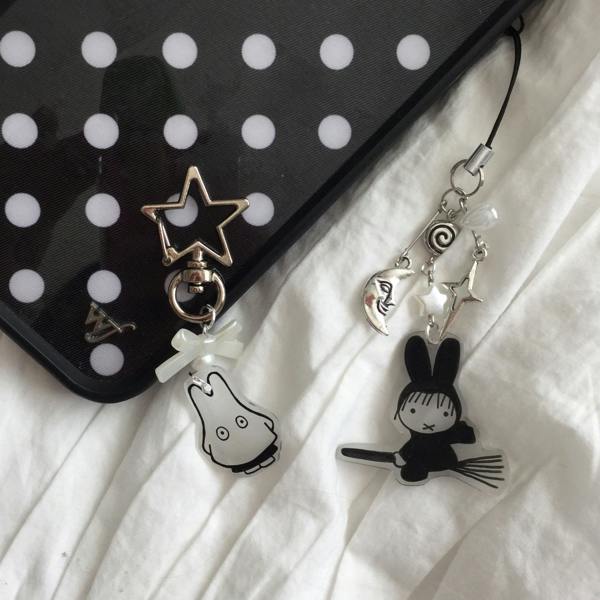 Phone case with polka dot design and decorative charms on a white fabric background