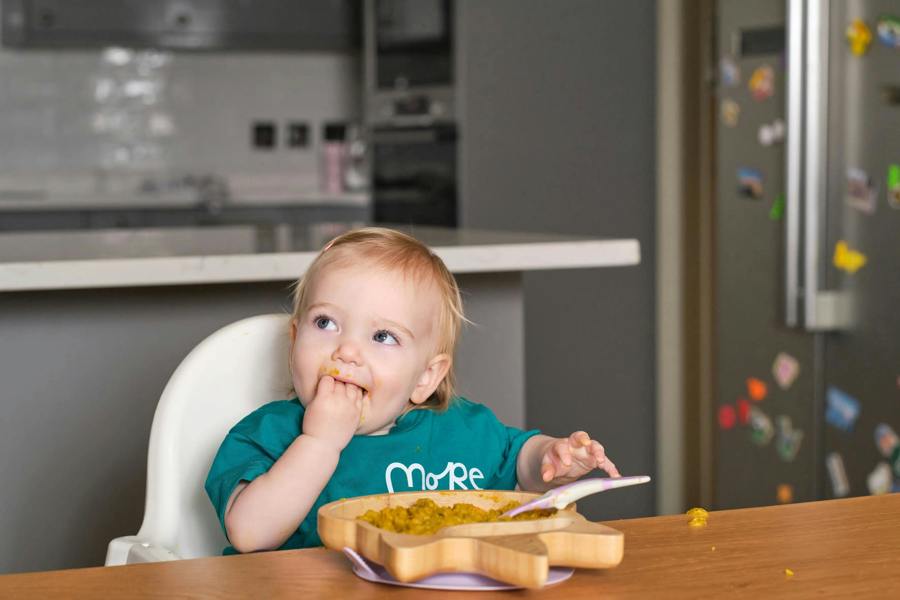 toddler eating more toddler meal dhal at the kitchen table for dinner