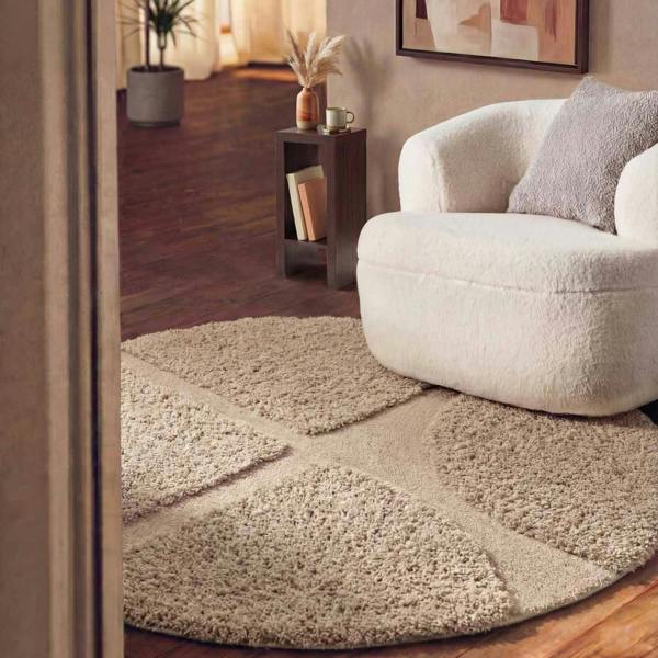 Beige geometric-patterned rug in a living room with a white armchair and side table.