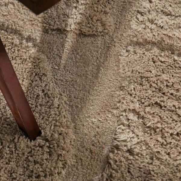 Close-up of a textured beige carpet with a wooden chair leg visible.