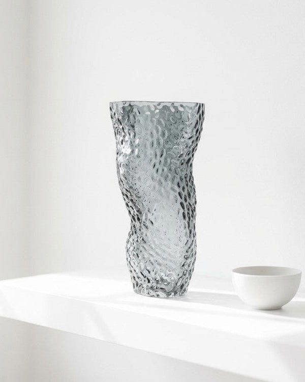 Textured glass vase with flowers against a light gray background