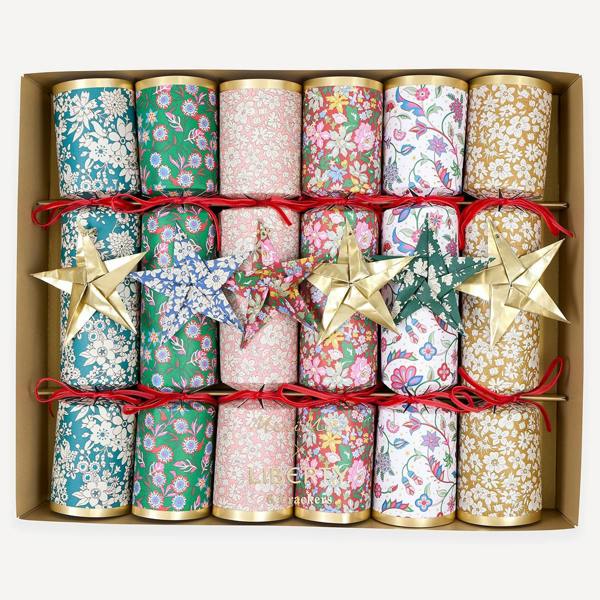 A premium gold box containing a set of six luxury Christmas crackers in six different colorful Liberty floral prints, each decorated with red velvet bows and an origami star.