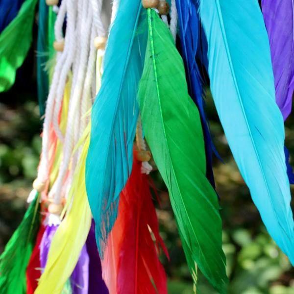 Close-up of rainbow feather tassels on a multicolor dream catcher pyramid