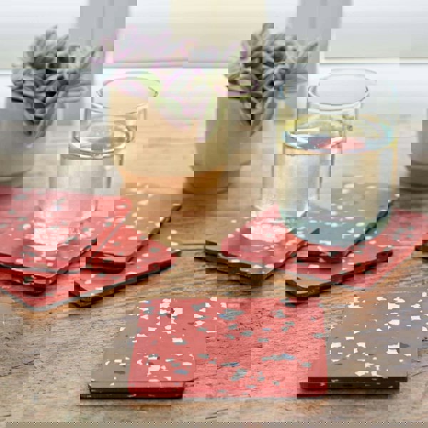 A set of red and white confetti coasters on a wooden table made from recycled plastic.