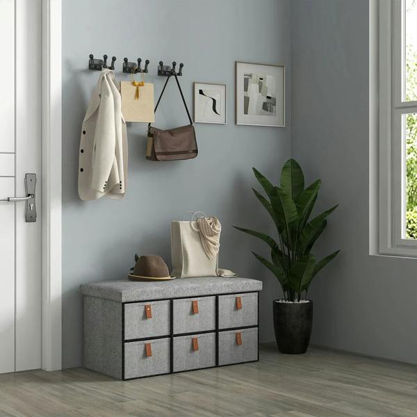 Light grey shoe storage bench with cushioned lid and six fabric drawers in bedroom corner