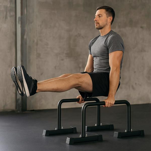 Large parallettes in use by a man in a gray shirt and black shorts, demonstrating strength training with elevated leg holds on a smooth floor