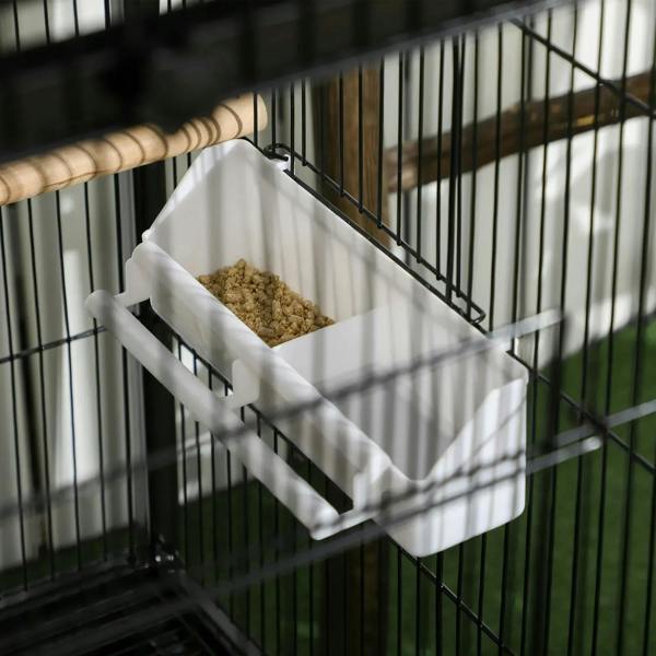 White removable tray inside black wire bird cage, filled with bird feed