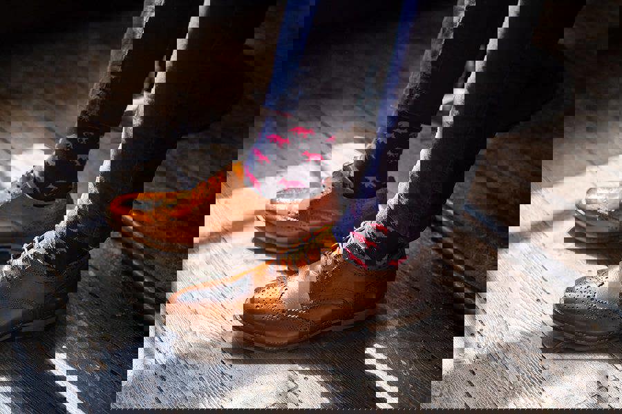 Brown leather shoes and fox patterned socks on a wooden floor