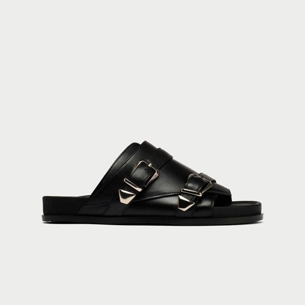 Black sandal with buckles on a light gray background