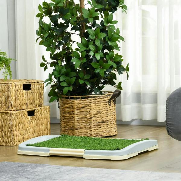 Green artificial grass puppy training pad with white plastic tray on floor