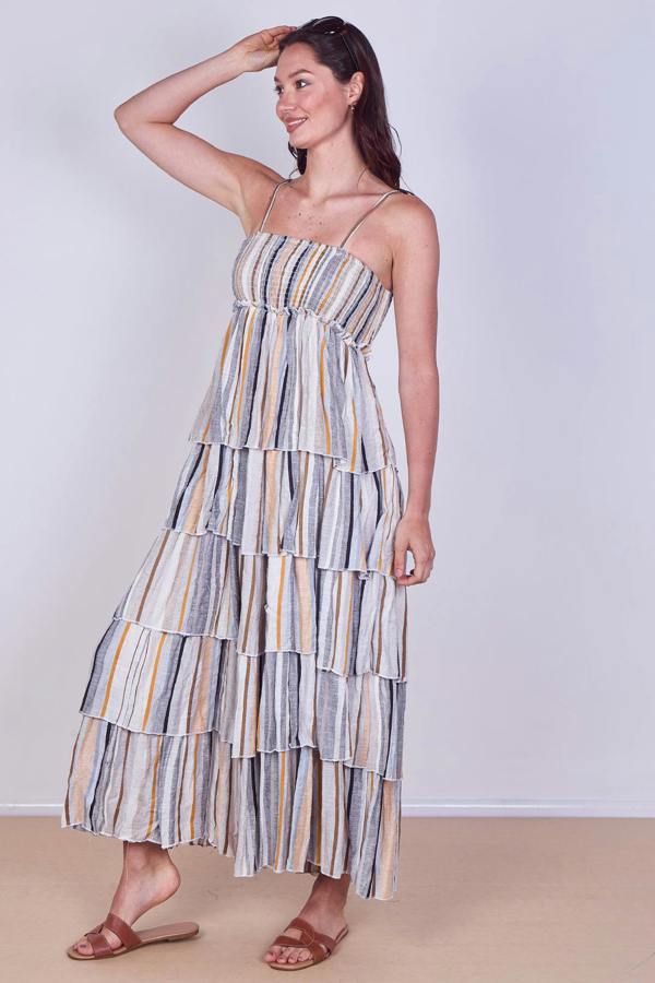 Woman wearing a striped tiered dress against a plain background