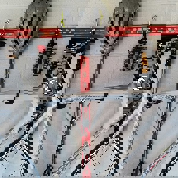 Horizontal folding bike hooks, work stand and double gear storage.. Close up of a Horizontal bike rack, wall mounted bike storage with a road bike, helmet and tools