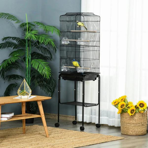 Black bird cage on wheeled stand with two perches and a single bird perched inside