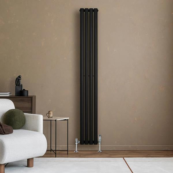 Sleek black oval single column radiator standing against a textured beige wall, enhancing modern interior decor with its minimalist design