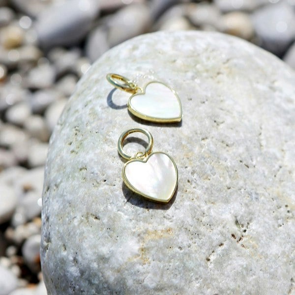 Mother of pearl heart charm hoops on a rock.