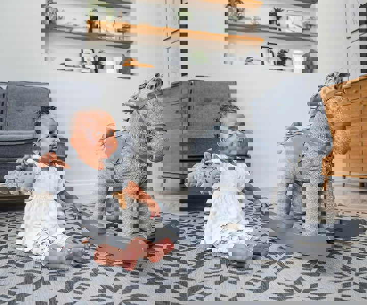 little girl sat with teddy bear next to grey rocking horse for toddlers