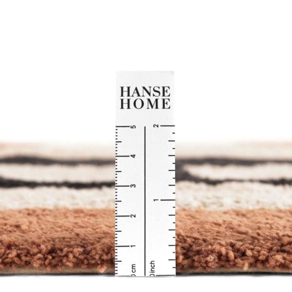 Close-up of a rug with a ruler displaying measurements, branded 'HANSE HOME'.