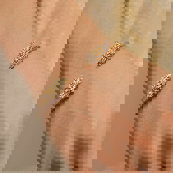 Double Angel Wing Bangle by BLOOMTINE modelled on wrist, crafted from gold over sterling silver and hand-set with brilliant-cut moissanites. A tarnish-resistant, adjustable gold cuff designed as a spiritual talisman, showcasing premium craftsmanship and ethical sparkle