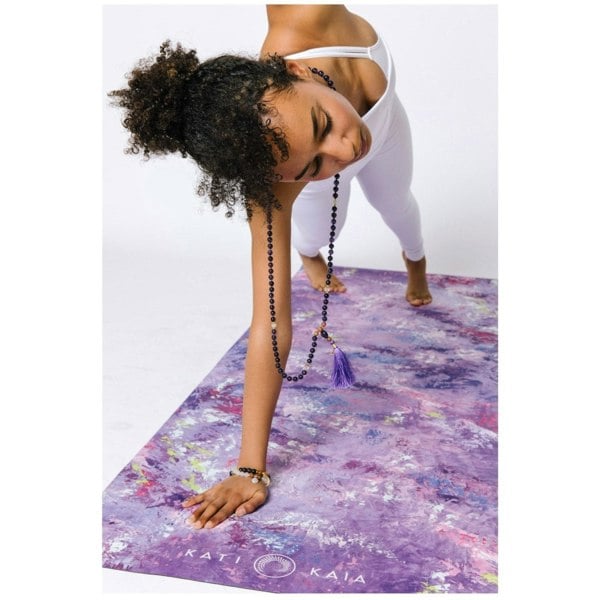 Woman practising yoga on purple mat wearing Kati Kaia amethyst mala necklace with tassel