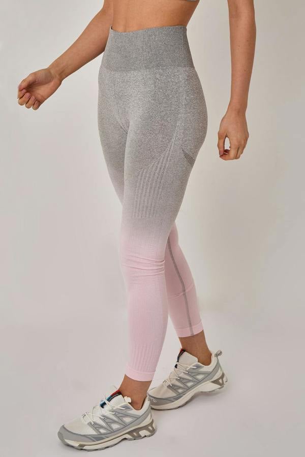 Person wearing gray and pink gradient leggings with white sneakers on a light background