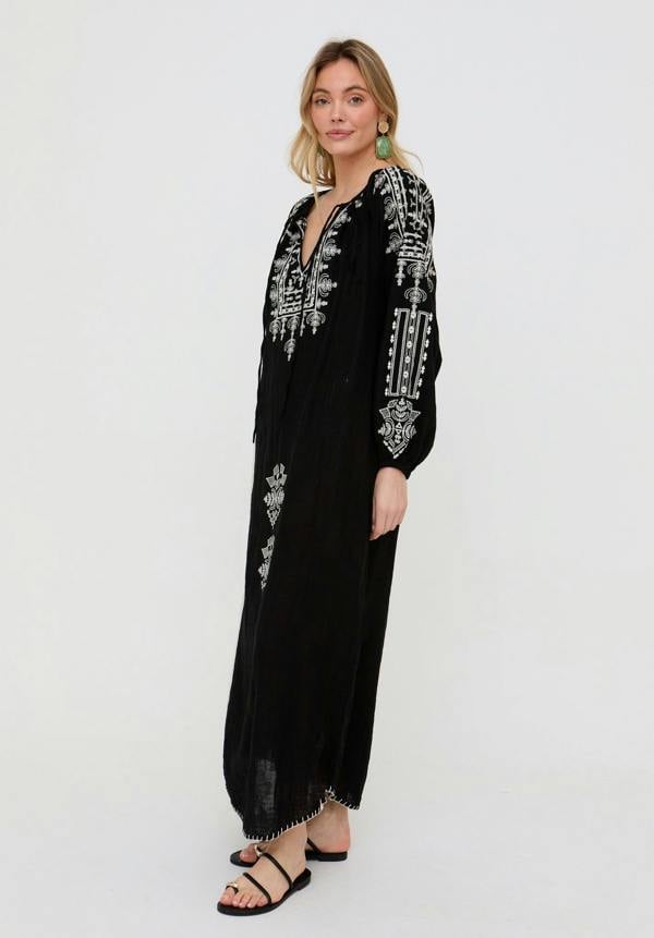 Woman wearing a black dress with white embroidery on a white background