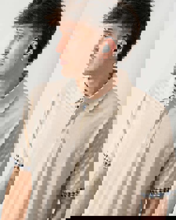 close up shot of a model wearing an Aquascutum Mens Club Check Stretch Piquet Sleeves Polo Shirt in Beige 03