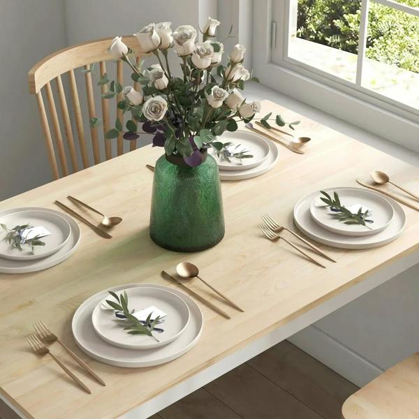 Natural wood tabletop with place settings and white chairs around it