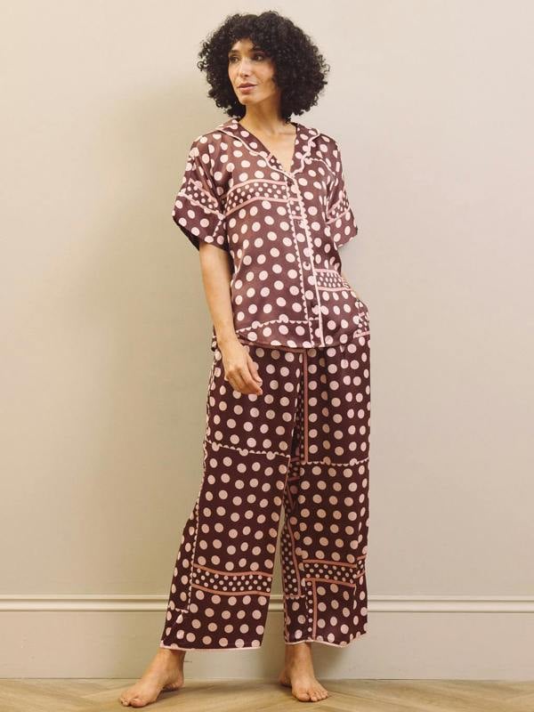 Woman wearing a polka dot pyjama set against a plain background