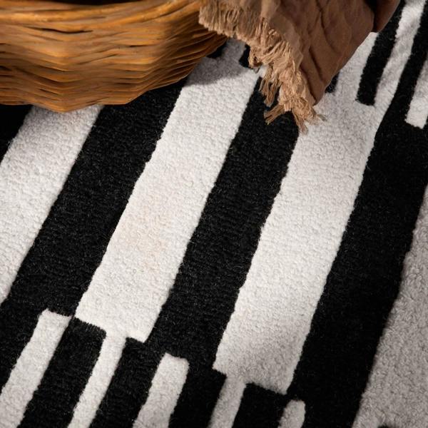 Close-up of a black and white striped rug with a woven basket on top.