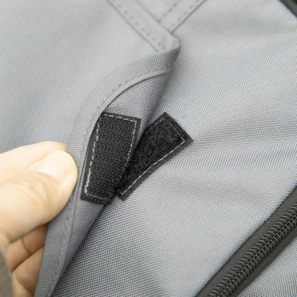 Close-up of grey stroller seat fabric with stitched strap and fastening tab
