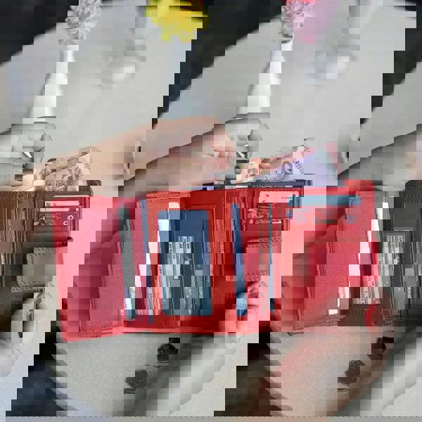 Person holding soft red leather trifold purse with secure tab fastening