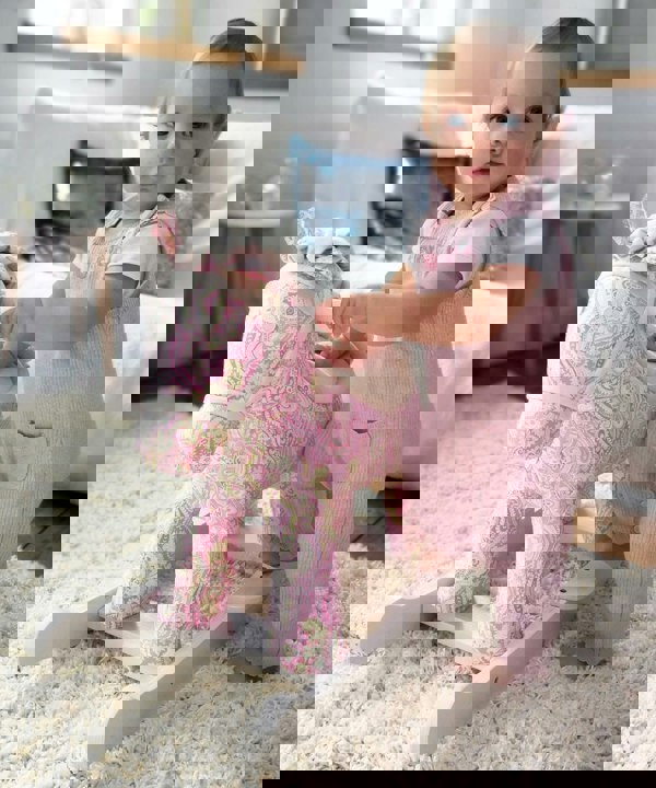 Baby girl standing next to pink Pixie & Fluff Babys Rocking Horse